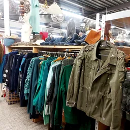 Rekken met tweedehands jassen en jasjes in verschillende kleuren, voornamelijk donkerblauw, groen en khaki