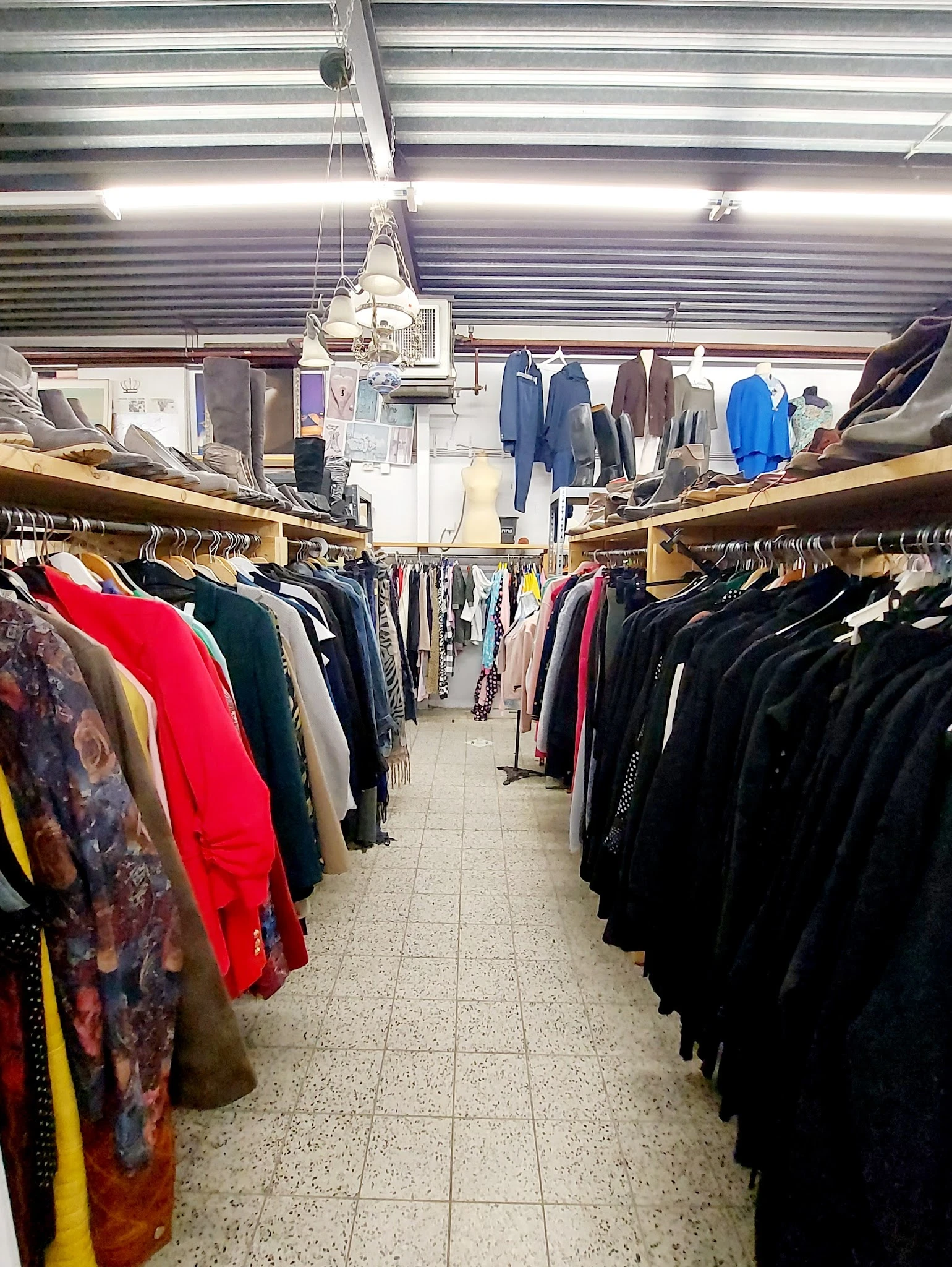 Rekken met tweedehands kleding in verschillende kleuren in een kringloopwinkel