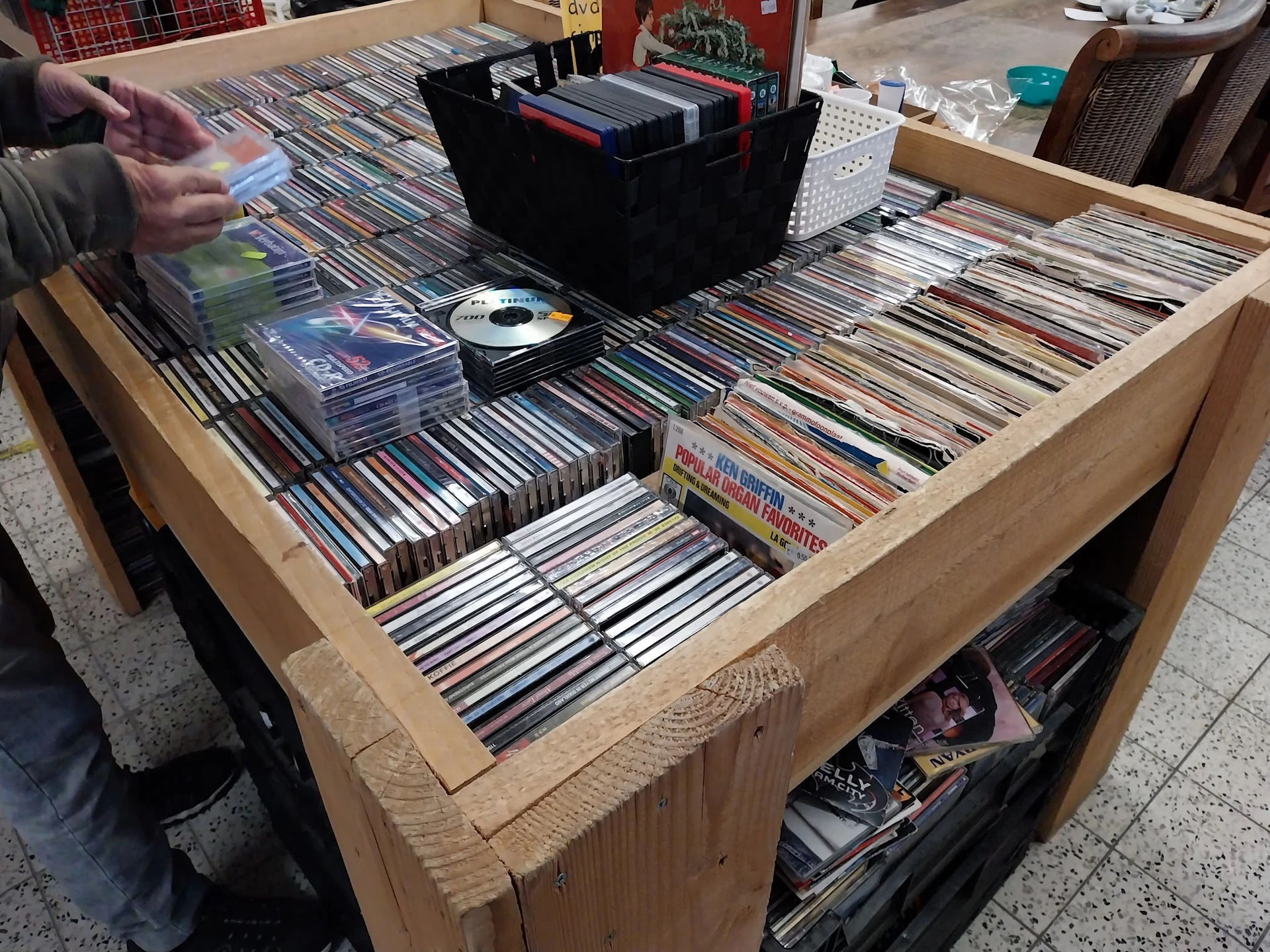 Houten display tafel vol met cd's en dvd's, met een zwarte opbergdoos en losse schijven