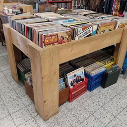 Houten display met tweedehands vinyl records, cd's en dvd's uitgestald op meerdere niveaus