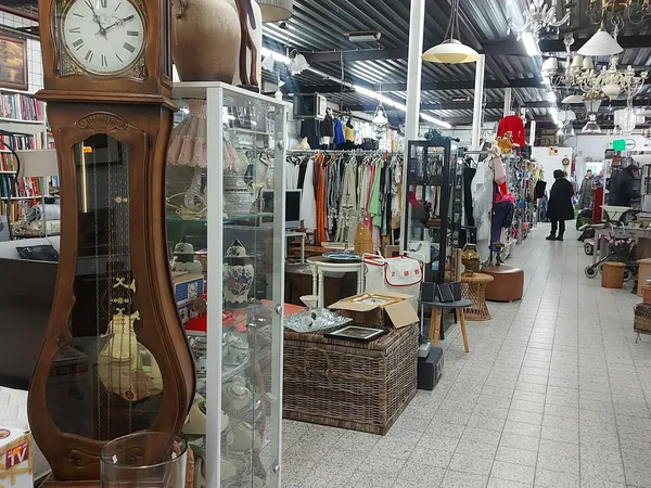 Winkelvloer van kringloopwinkel met kleding aan rekken, meubels, boeken en diverse tweedehandsartikelen