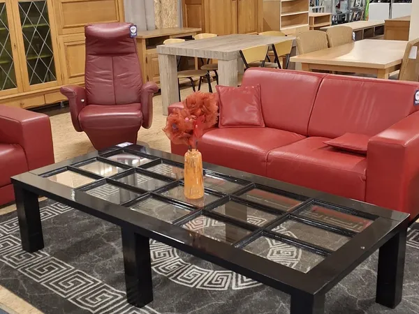 Woonkamer met rode leren bank, fauteuil, salontafel en meubels op achtergrond