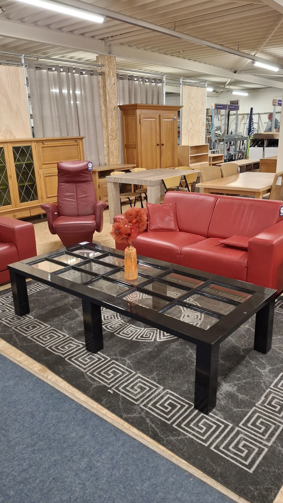 Woonkamer met rode leren bank, fauteuil, salontafel en meubels op achtergrond