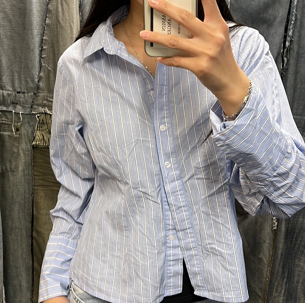 Close-up van een lichtblauwe gestreepte blouse met witte knopen