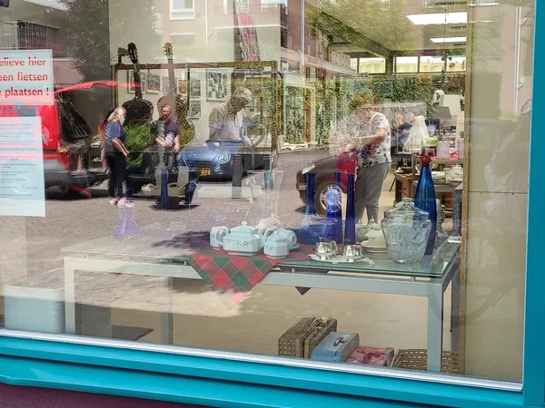 Winkelinterieur met glazen toonbank, displayitems en klanten zichtbaar achter het raam