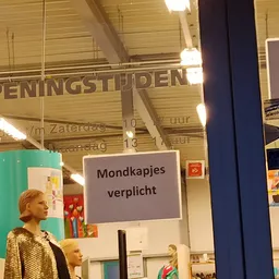 Winkelinterieur met een kind en uitstallingen; borden met Nederlandse tekst zichtbaar