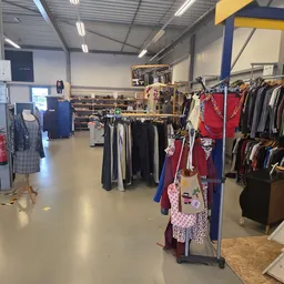 Winkelvloer van kringloopwinkel met kledingrekken en stellingen vol tweedehands kleding