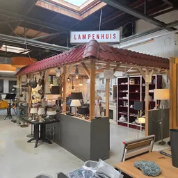 Winkelvloer met een houten tentstructuur (Lampenhuis-display) met verlichte lampen, rekken met decoratie en meubilair in een 
