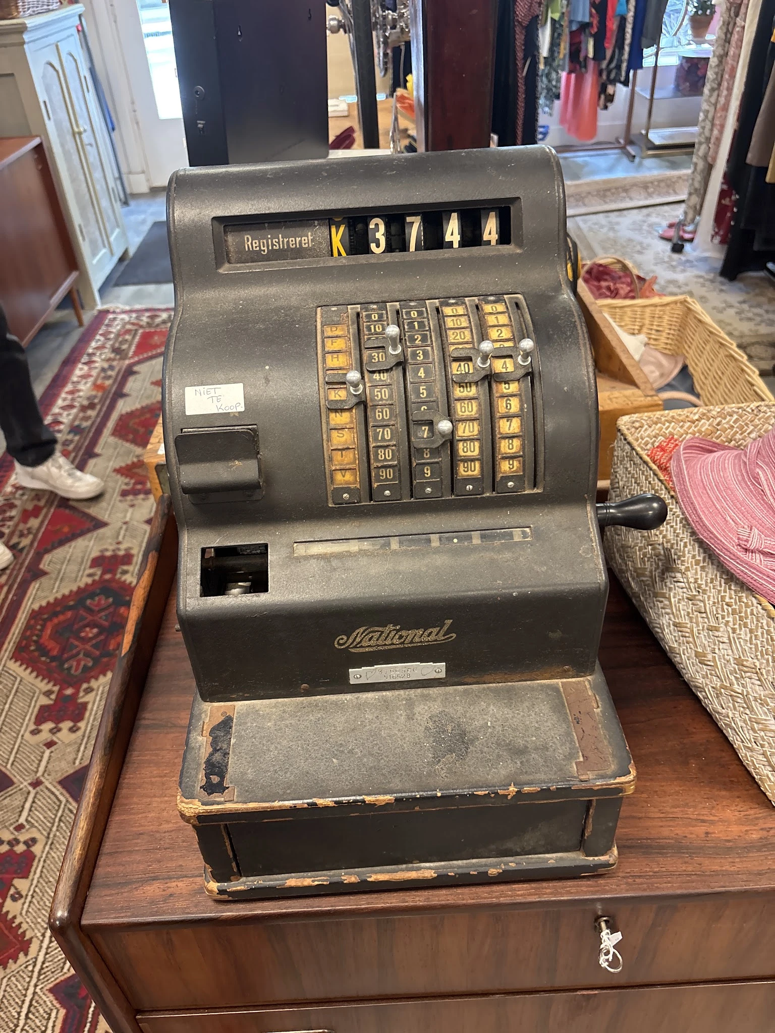 Vintage National kassaregister met gouden toetsen op houten tafel in kringloopwinkel