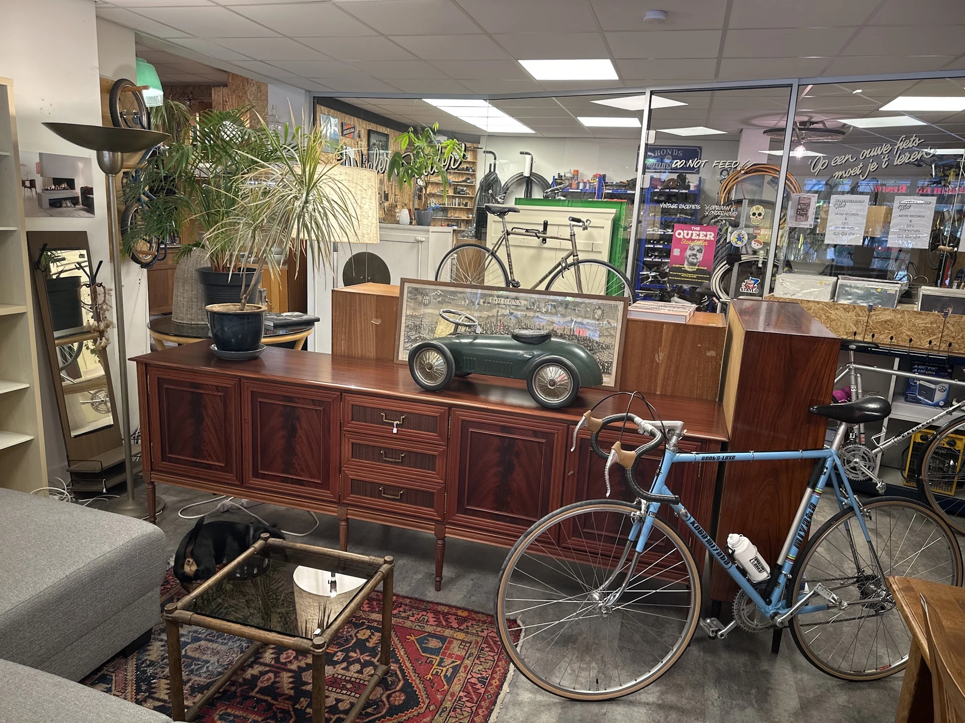Winkelvloer met houten dressoir, vintage speelgoedauto, fietsen en groenplanten