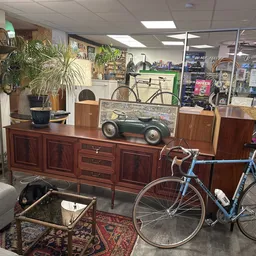 Winkelvloer met houten dressoir, vintage speelgoedauto, fietsen en groenplanten