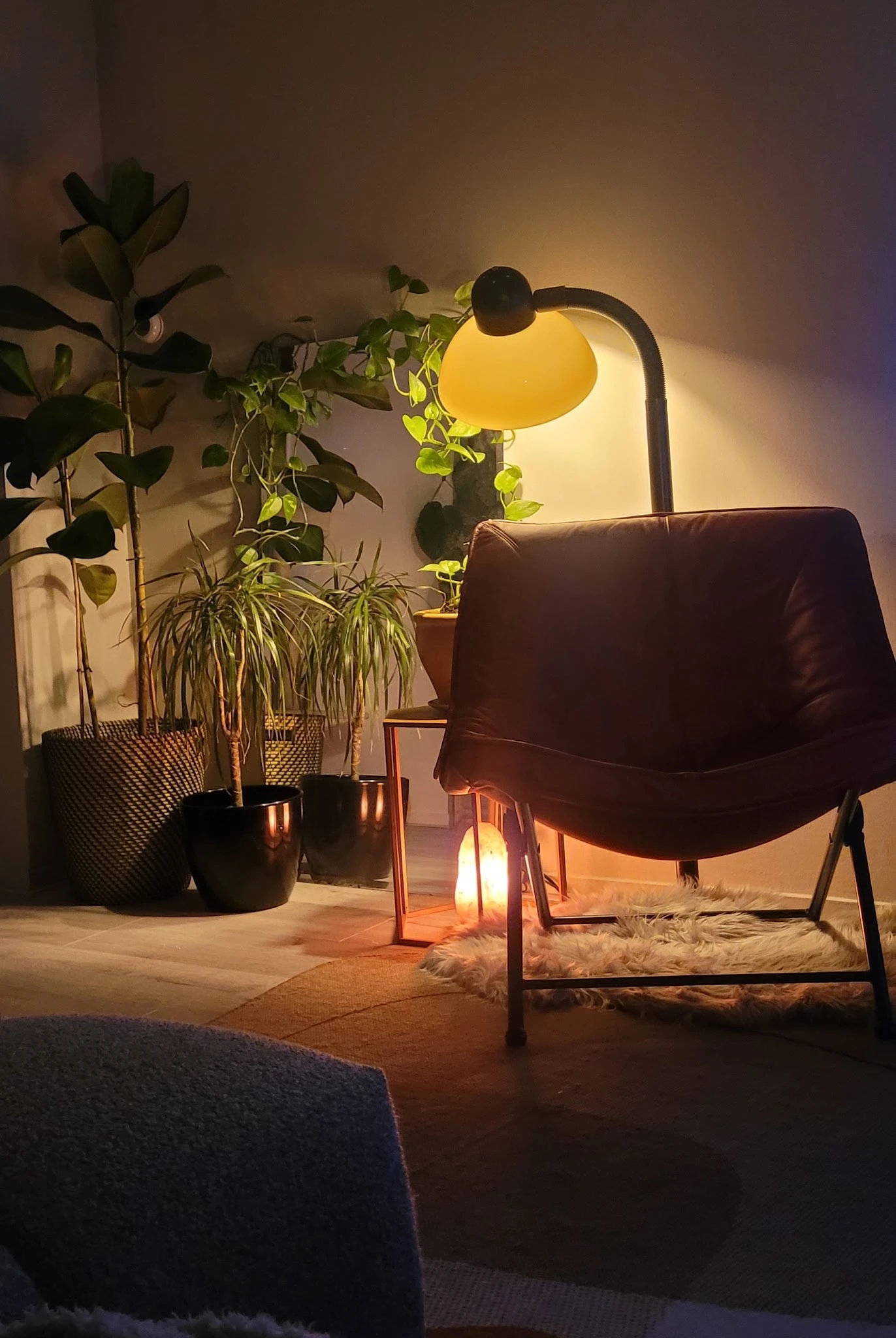 Bruine fauteuil met gele hanglamp en potplanten in warme interieursfeer