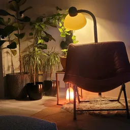 Bruine fauteuil met gele hanglamp en potplanten in warme interieursfeer