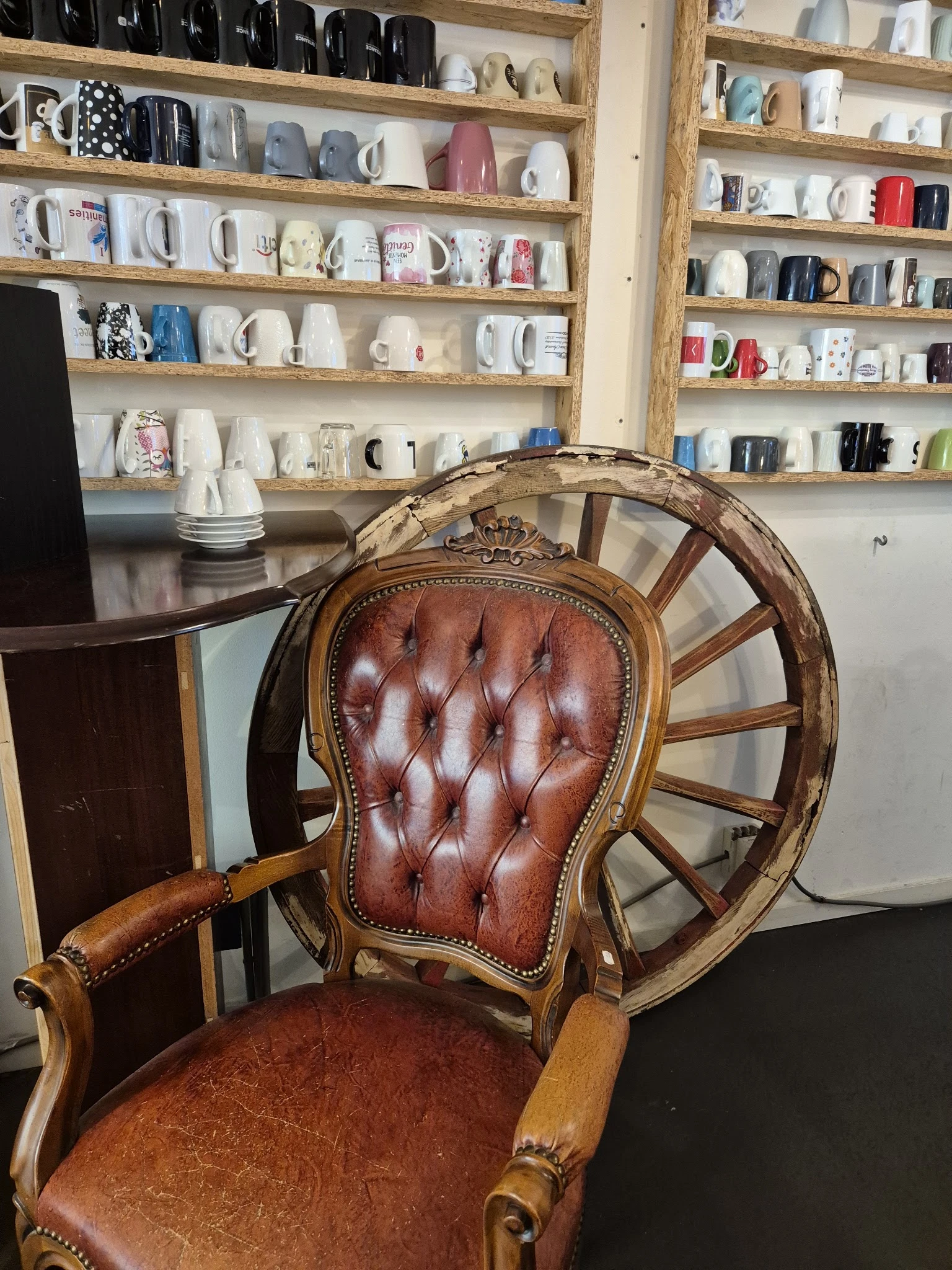Bruine leren fauteuil met capitonnage en houten wielen, close-up van de stoel met kasten op de achtergrond