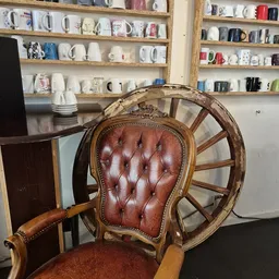 Bruine leren fauteuil met capitonnage en houten wielen, close-up van de stoel met kasten op de achtergrond