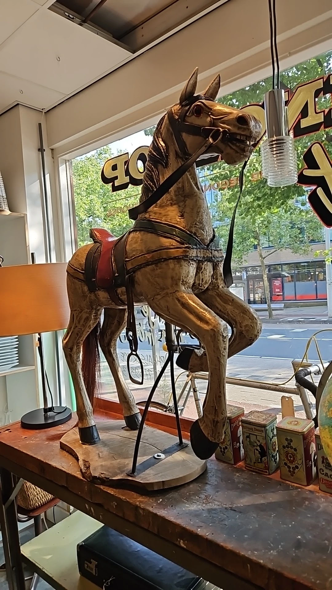 Bronzen beeldhouwwerk van een paard met zadel en toom, staande op een voetstuk in de winkel