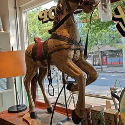 Bronzen beeldhouwwerk van een paard met zadel en toom, staande op een voetstuk in de winkel