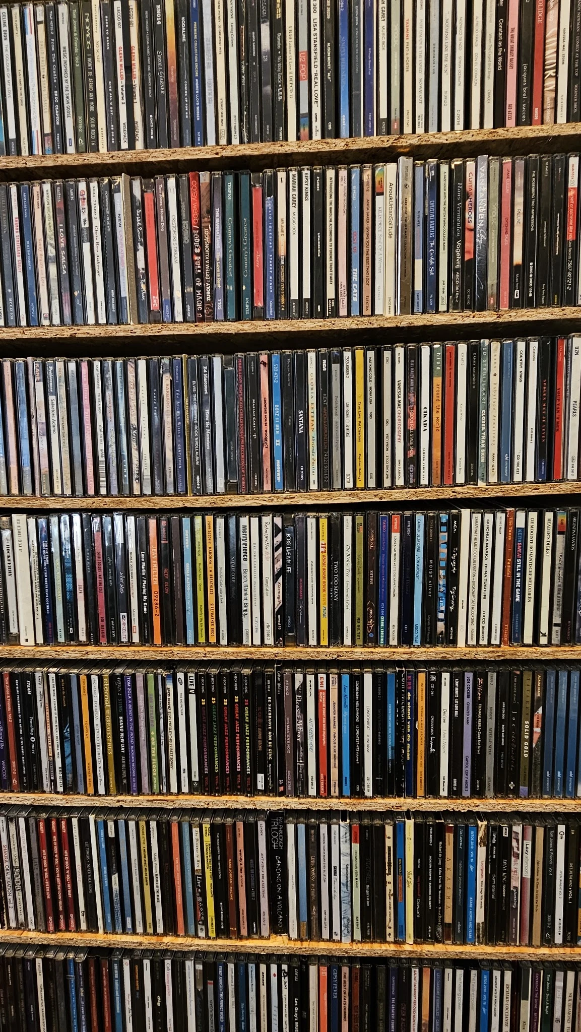 Vier volle rekken met grote verzameling cd's en dvd's netjes op elkaar gestapeld