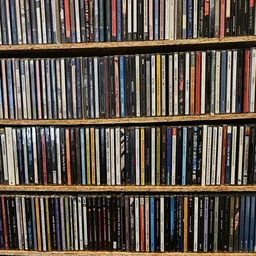 Vier volle rekken met grote verzameling cd's en dvd's netjes op elkaar gestapeld