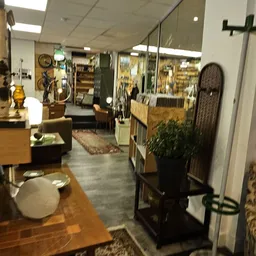Binnenaanzicht van kringloopwinkel met houten meubels, stellingen met spullen en diverse inrichtingsartikelen