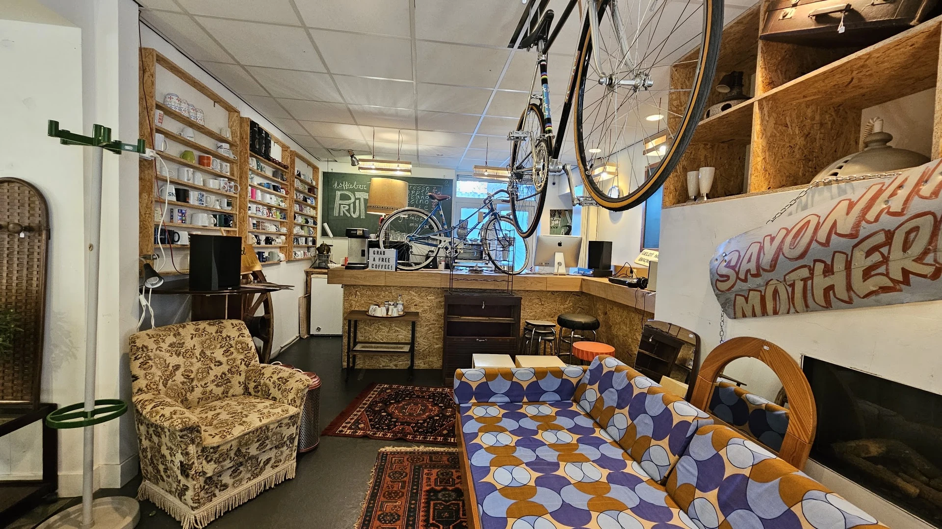 Winkelbinnenkant met stellingen, boeken, meubels en een fiets aan het plafond