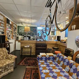 Winkelbinnenkant met stellingen, boeken, meubels en een fiets aan het plafond