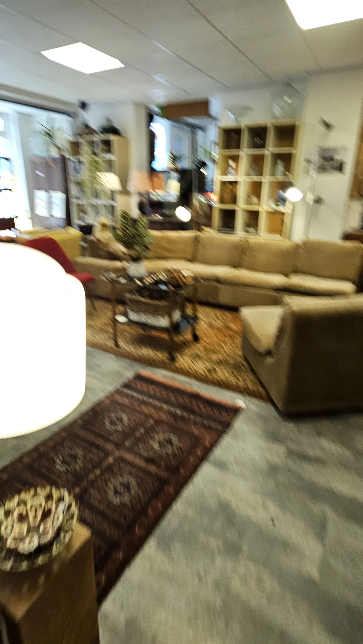 Woonkamer met beige bank, houten tafels en Oosterse tapijten op houten vloer
