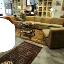 Woonkamer met beige bank, houten tafels en Oosterse tapijten op houten vloer