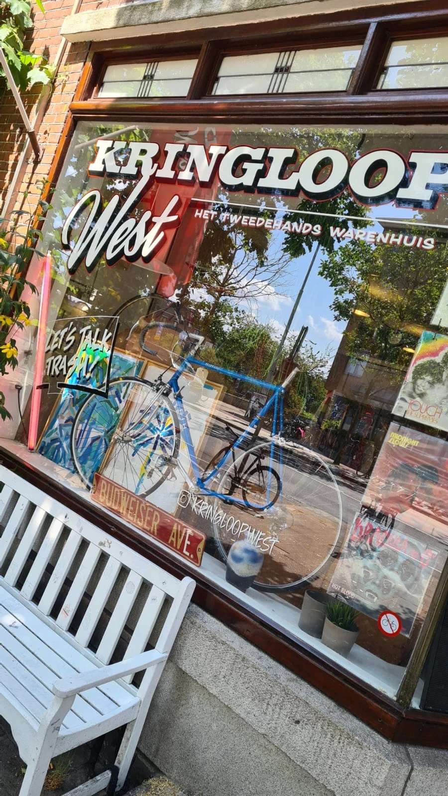 Blauwe fiets tegen raam van winkel met graffiti en reclames