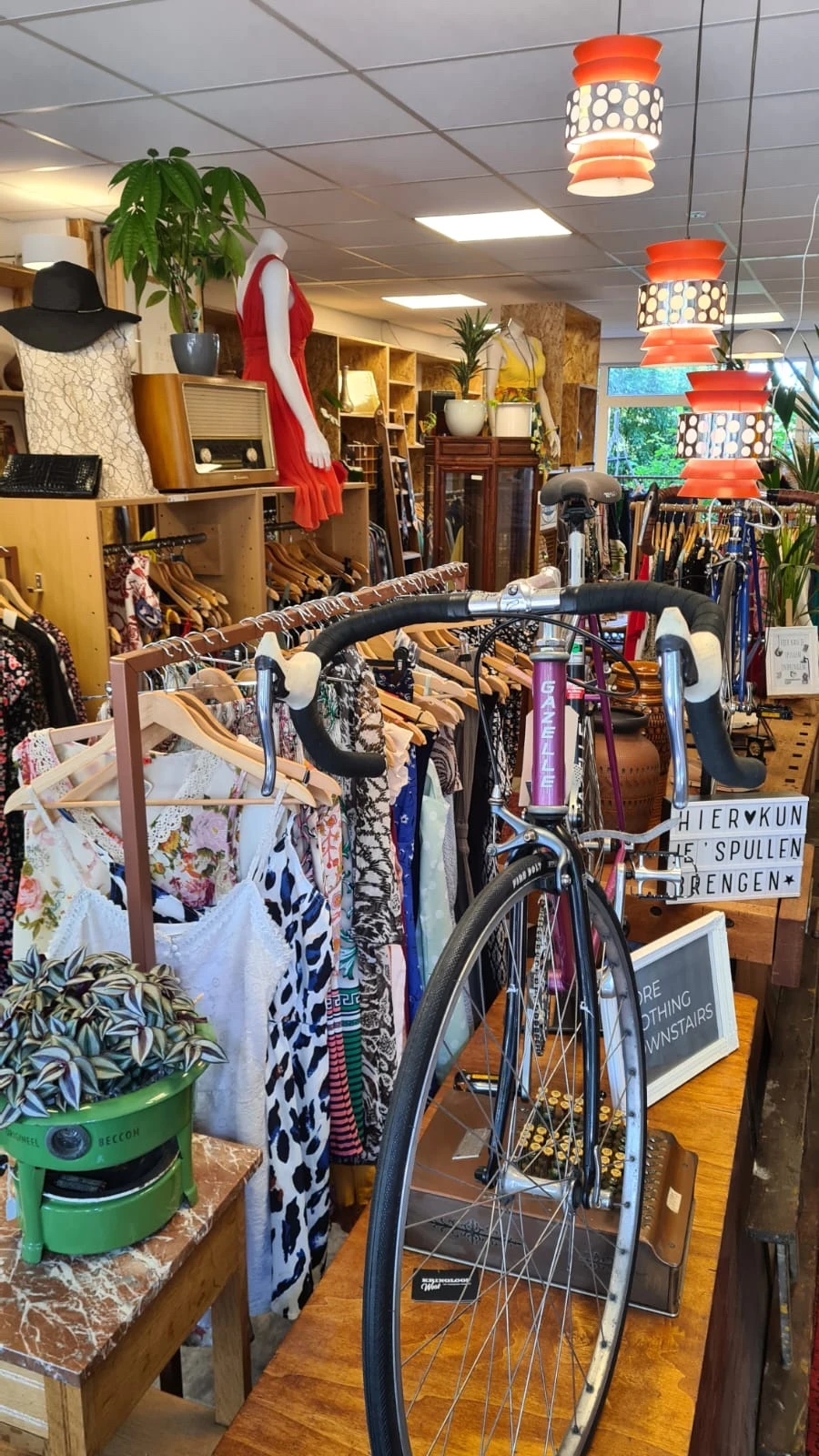 Rekken met tweedehands kleding, fietsen en huishoudspullen in een kringloopwinkel
