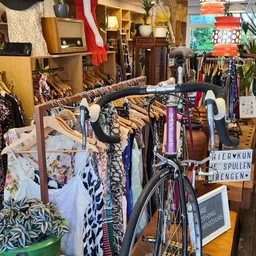 Rekken met tweedehands kleding, fietsen en huishoudspullen in een kringloopwinkel