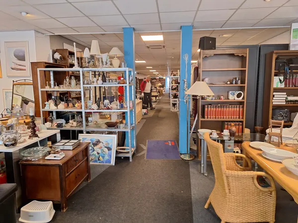 Winkelvloer met stellingen vol huishoudelijke spullen, meubels en decoratie in een kringloopwinkel