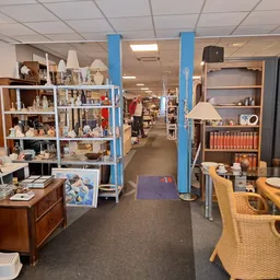 Winkelvloer met stellingen vol huishoudelijke spullen, meubels en decoratie in een kringloopwinkel