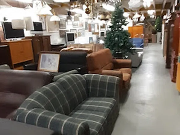 Winkelvloer van kringloopwinkel met uitgestalde meubels: stoelen, fauteuils en kasten langs het gangpad
