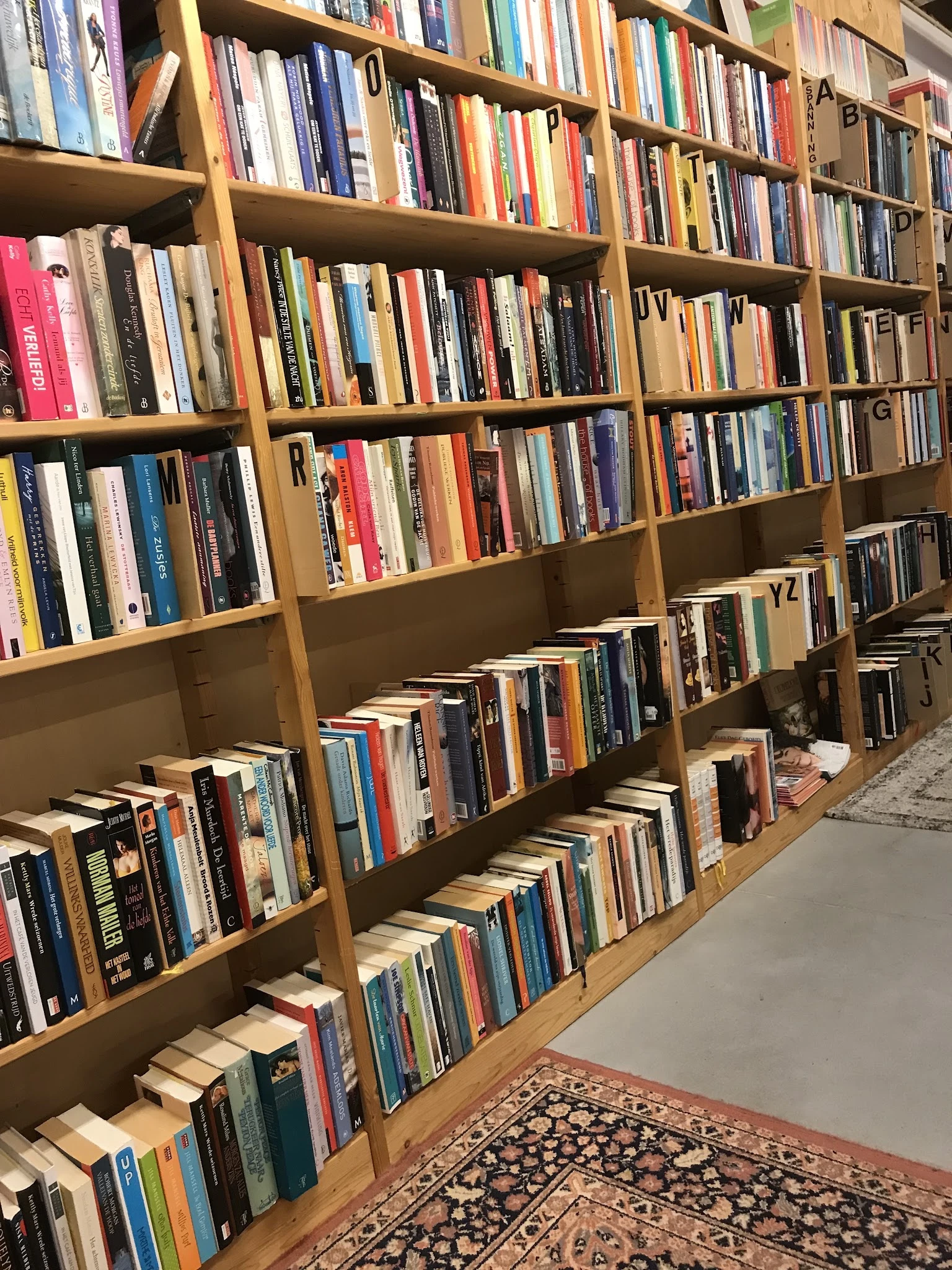 Houten boekenkast met honderden tweedehands boeken en dvd's netjes uitgestald op meerdere planken