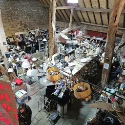 Overzicht van een rommelige kringloopwinkel met verschillende meubels, huishoudartikelen en spullen verspreid door de ruimte
