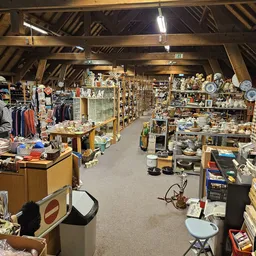 Overzicht van de winkelvloer met stellingen vol huishoudartikelen, servies, decoratie en kleding aan de linkerkant