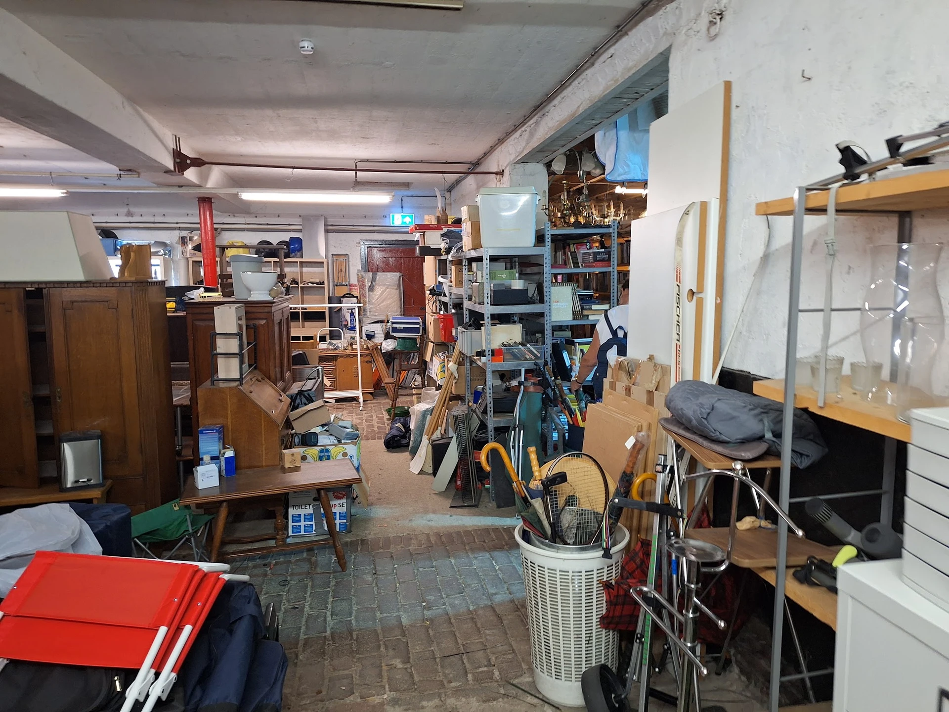 Rommelige winkelvloer met verschillende meubels, fietsen, stellingen en opgestelde spullen