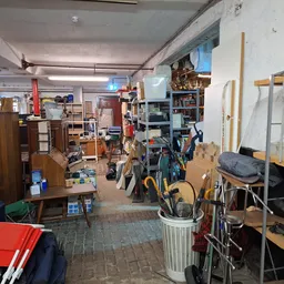 Rommelige winkelvloer met verschillende meubels, fietsen, stellingen en opgestelde spullen