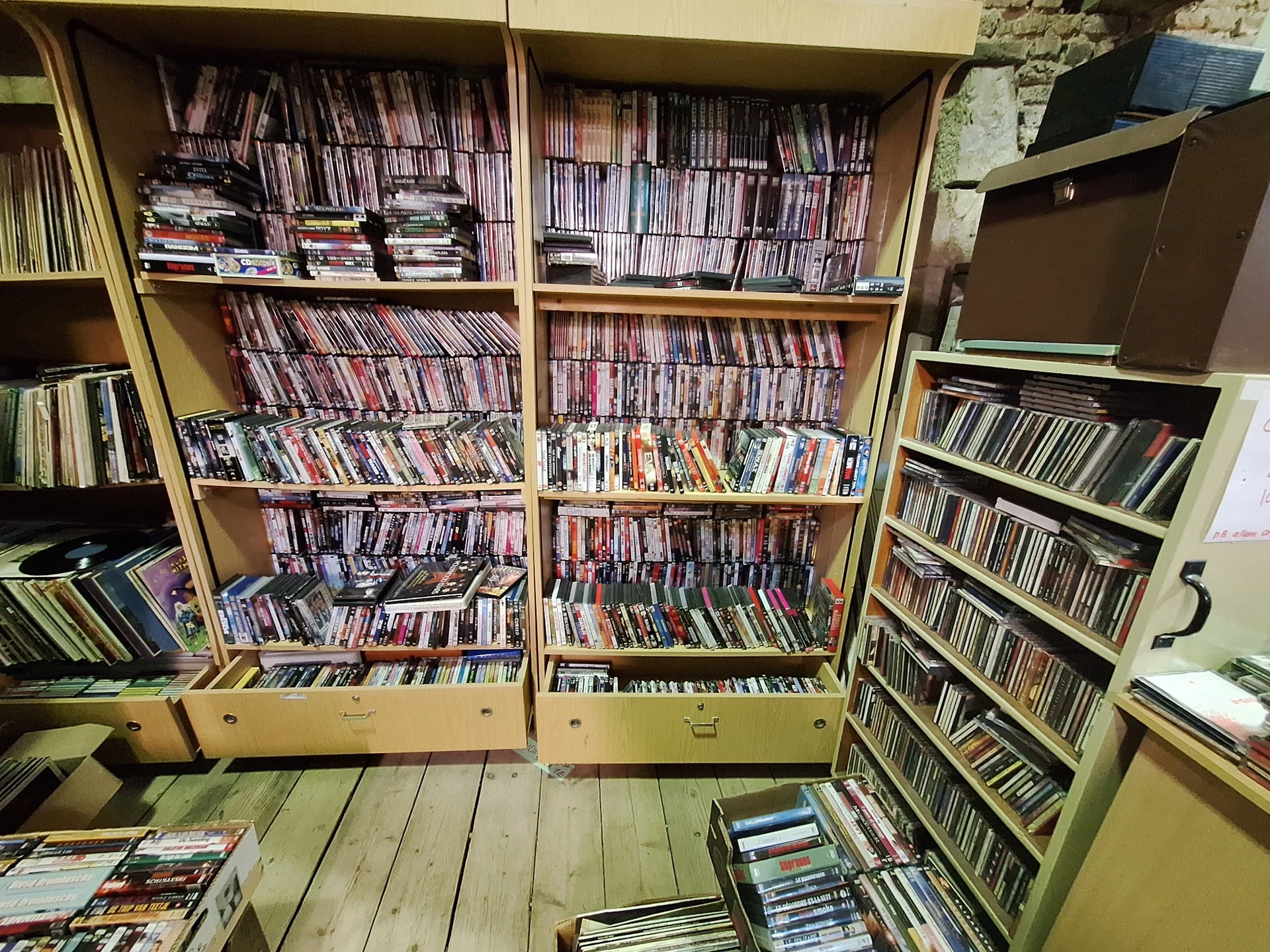 Grote kast met honderden cd's en dvd's netjes op rijen uitgestald in een kringloopwinkel
