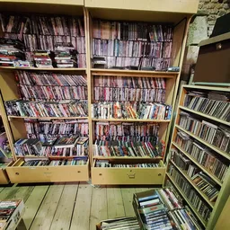 Grote kast met honderden cd's en dvd's netjes op rijen uitgestald in een kringloopwinkel