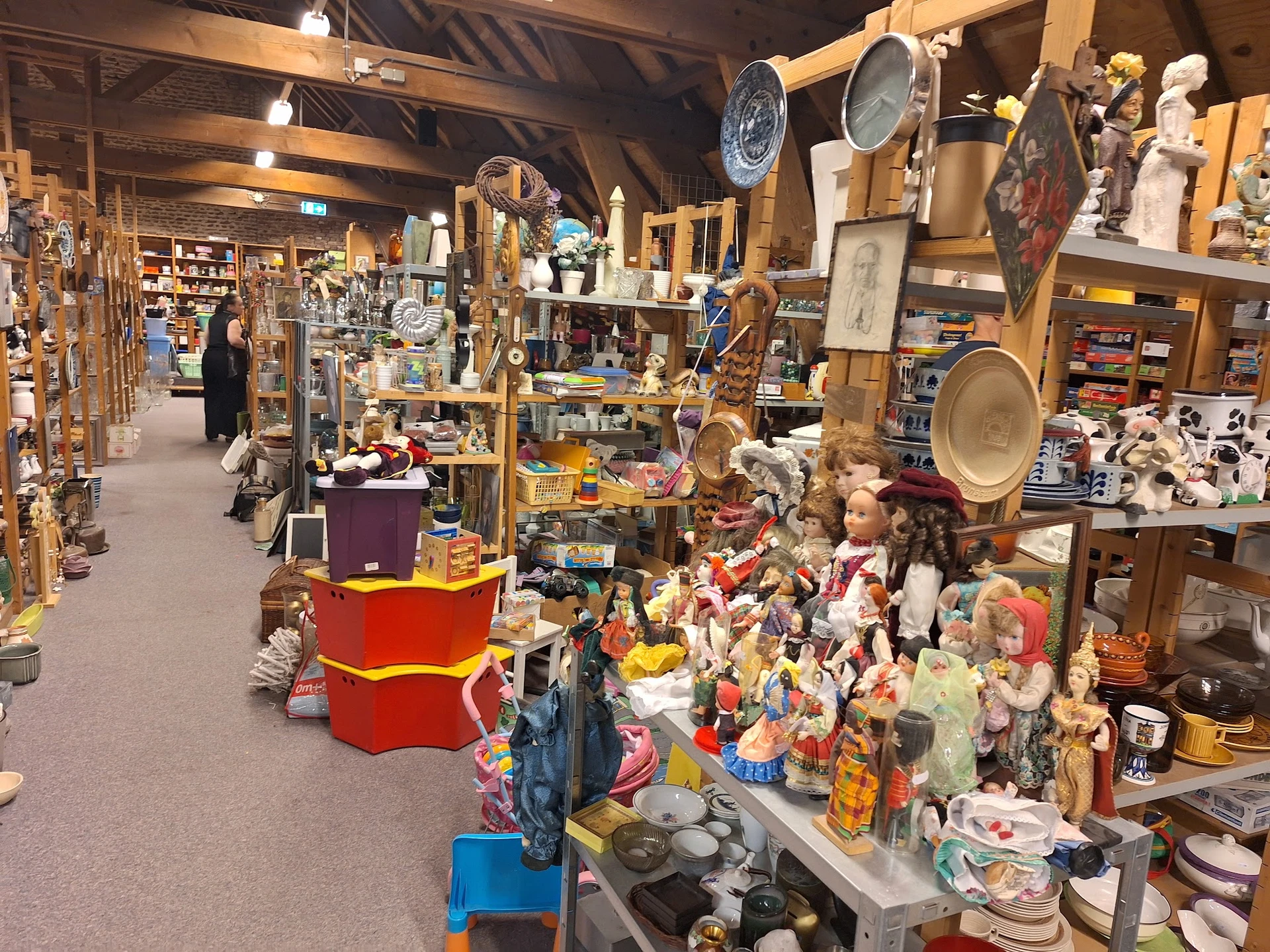 Winkelvloer van kringloopwinkel met diverse rekken, stellingen en uitgestalde spullen zoals servies, decoratie en gebruiksart