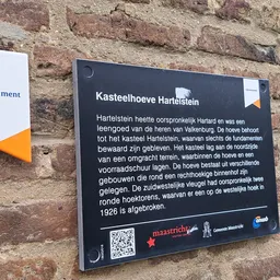 Informatieplaatje over Kasteelhoeve Hartelstein op bakstenen muur