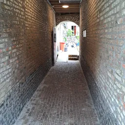 Bakstenen gang of doorgang met bogen naar een binnenplaats met wat spullen