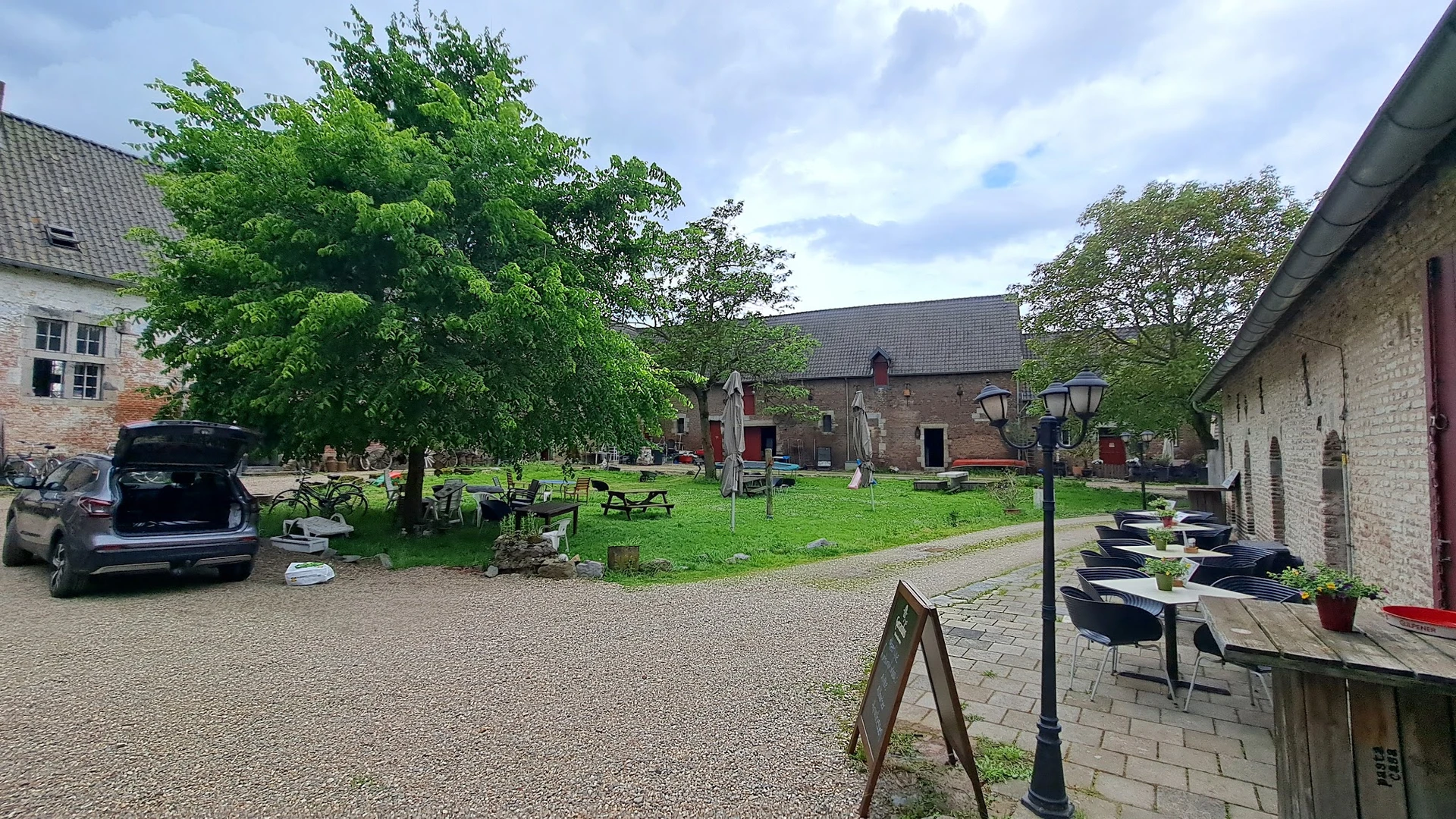 Bakstenen kerk met groene grasvelden, bomen en picknicktafels op het terrein