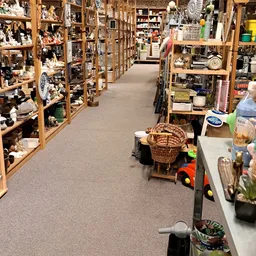 Winkelpad tussen houten stellingen met huishoudelijke spullen en decoratiematerialen in een kringloopwinkel