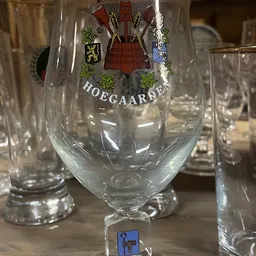 Glazen bierpullen met logo 'Hoegaarden' opgesteld op een tafel