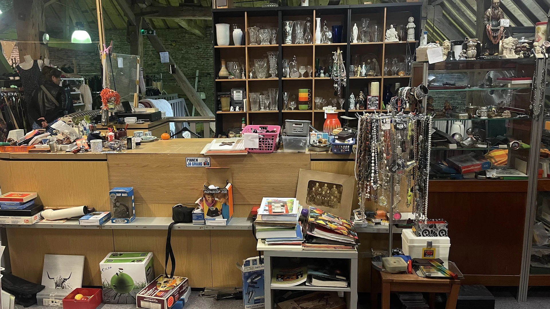 Toonbank en stellingen met tweedehands artikelen, sieraden, boeken en decoratieve voorwerpen