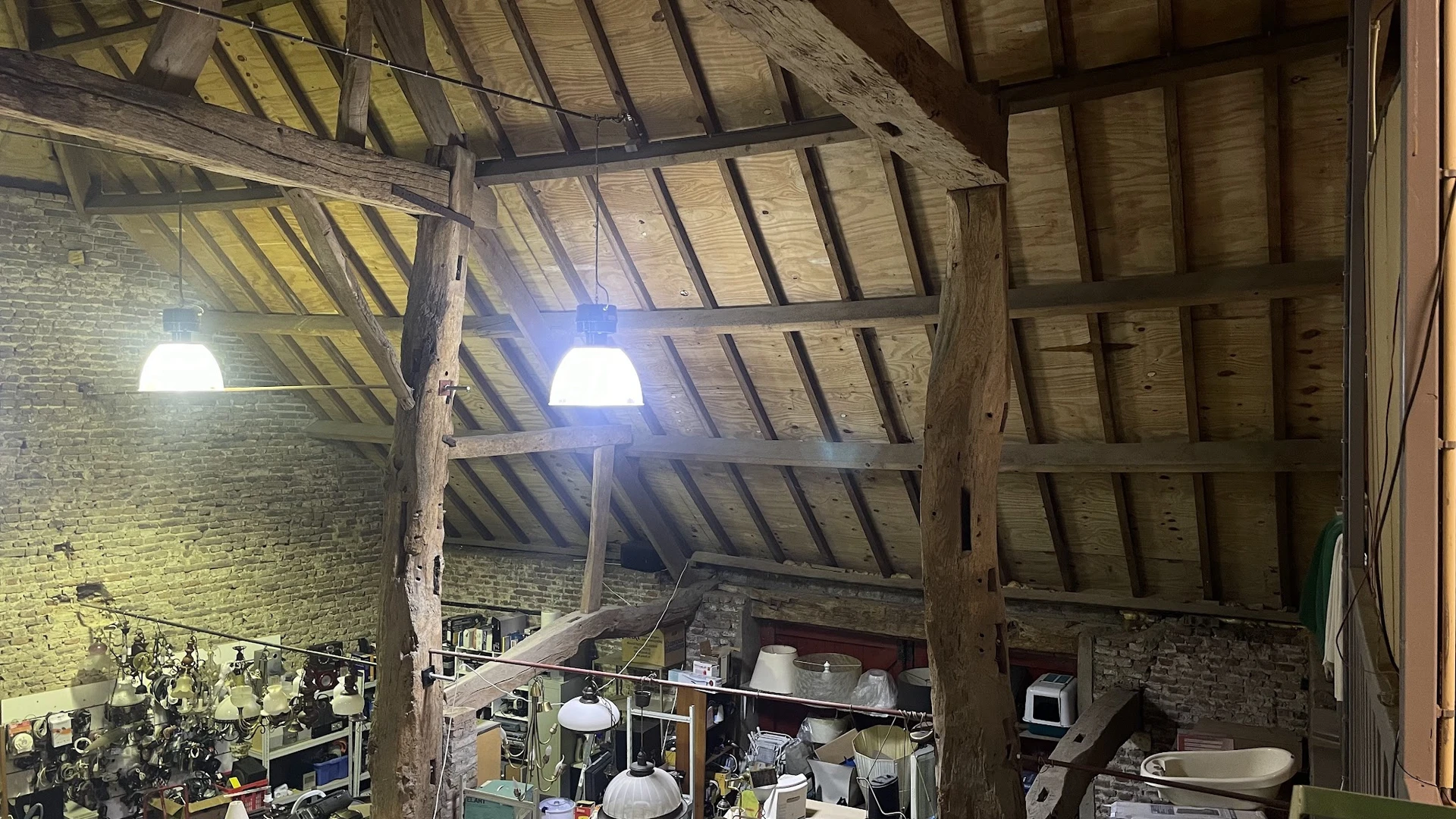 Zolder of bovenverdieping met houten balkenstructuur, blauwe lamp en opgeslagen spullen