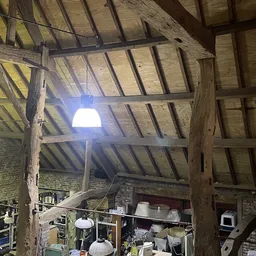 Zolder of bovenverdieping met houten balkenstructuur, blauwe lamp en opgeslagen spullen
